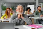 Man lacht naar de camera in een klaslokaal.